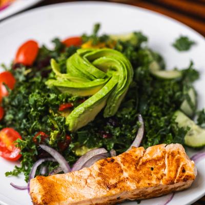 Salmon filet served with kale salad on the side.