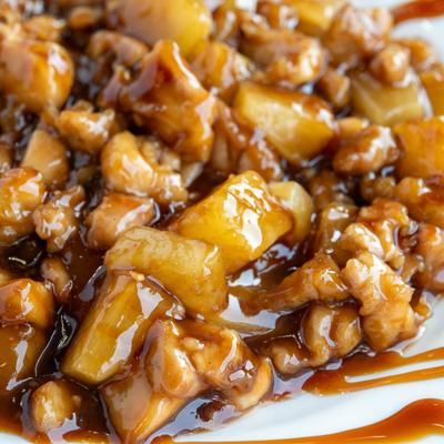 Pineapple chicken coated in a thick, glossy brown sauce, close-up.
