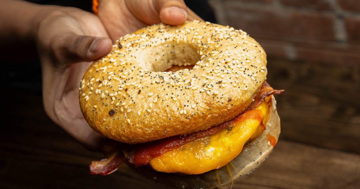 Hands holding a bagel sandwich