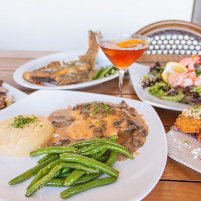 Chicken marsala with mashed potatoes and green beans, served with assorted dishes.