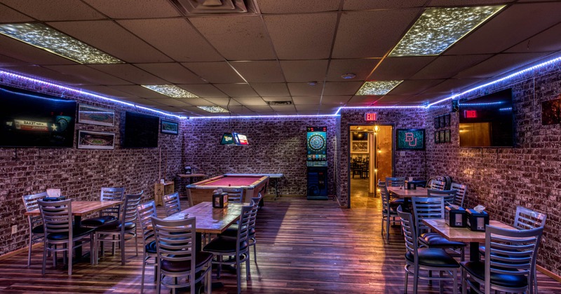 Interior, tables and seats, pool table and dart board machine, TVs on brick walls