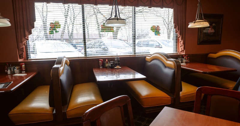 Interior of a diner with two adjacent booths, wood tables, yellow cushions