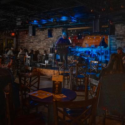 Interior, guests sitting at tables and enjoying a live music performance.