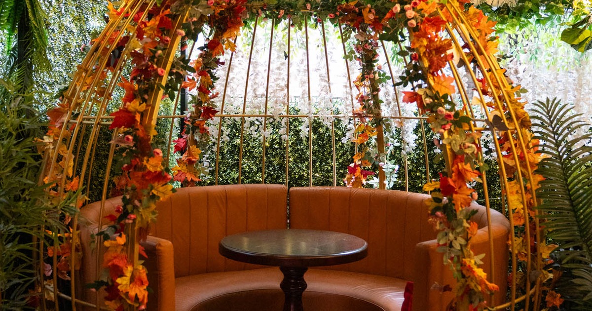 Interior, bird cage style seating booth with round wooden table and circular banquette bench
