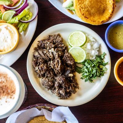 Barbacoa taco plate served beside other dishes, overhead view.