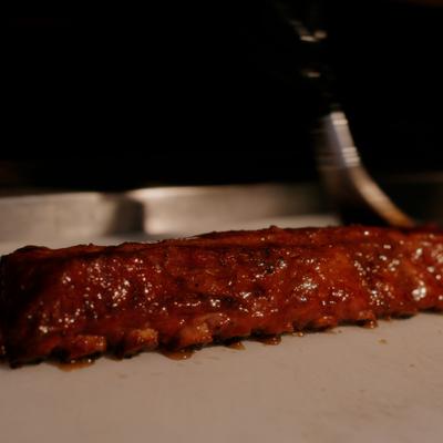 Rack of cooked and sauced pork ribs on a cutting board.