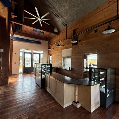 Interior featuring rustic wood paneled walls, a large ceiling fan and a counter.