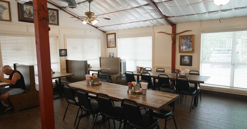 Interior space, cozy, rustic-style restaurant with wooden tables and simple black chairs