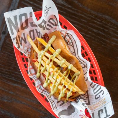 Bacon-wrapped hotdog, cheese, bell peppers, fries, avocado crema