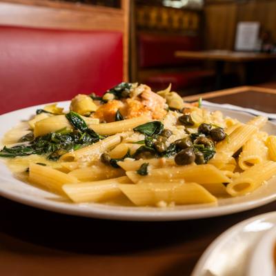 Salmon Piccata featuring pasta in light sauce with capers and spinach.