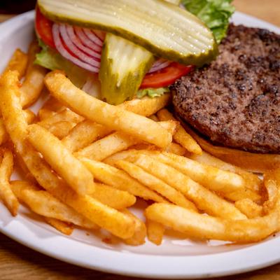 Crispy fries next to a burger patty with toppings on a white plate.