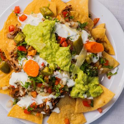 Loaded nachos topped with sour creme and guacamole, overhead view.