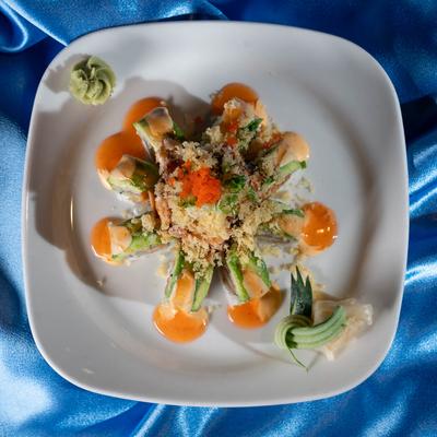 Sushi rolls topped with avocado, salmon, yellowtail, sriracha, sweet chili, tempura, and roe.
