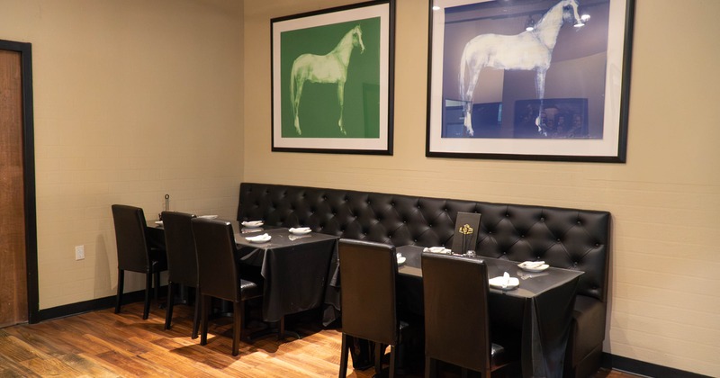 Interior, dining area featuring a tufted black bench, tables with black tablecloths, and chairs