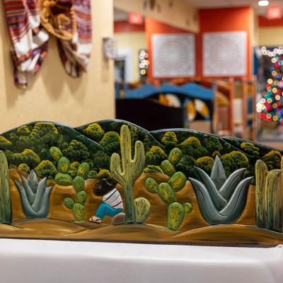 Wooden booth divider with painted desert landscape.