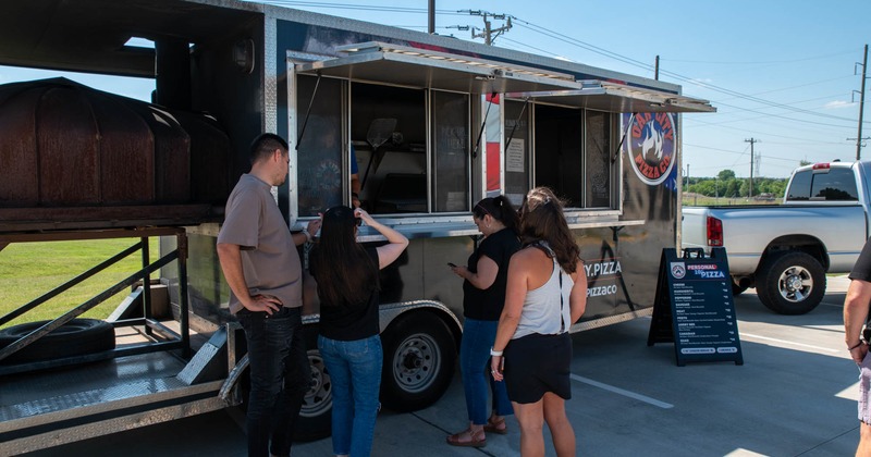 A group of customers queuing and waiting to order food from a food truck
