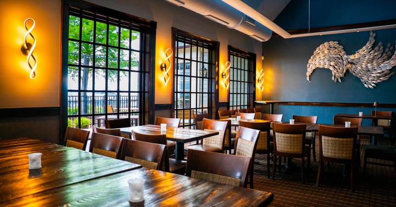 A modern dining room with wooden furniture, large windows, spiral wall lights