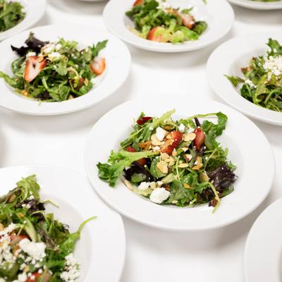 Fresh garden salads arranged on white plates across a banquet table.