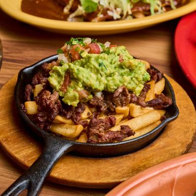 Carne asada fries topped with guacamole and pico de gallo.