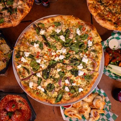 Pesto Supremo Pizza with ricotta, spinach, onion, chicken, and tomato.