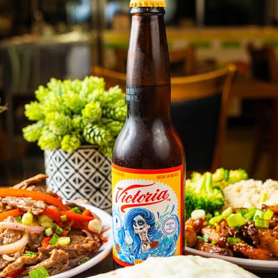 Beer bottle on a table with plates of colorful food.