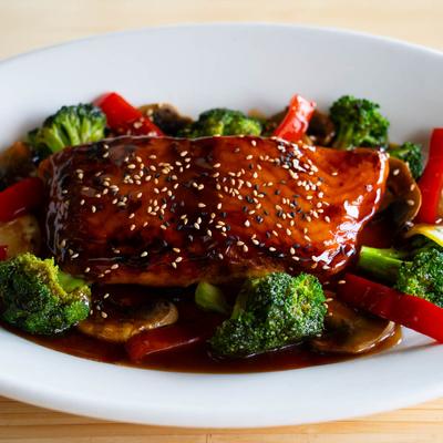 Teriyaki Salmon, served with stir fried vegetables, and topped with sesame seeds.