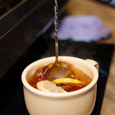 Hot tea stirred with lemon slices.