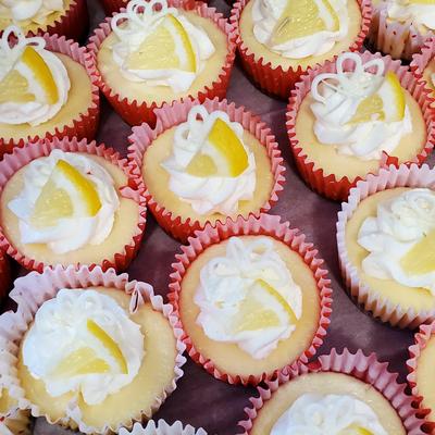 A tray of lemon cupcakes with swirls of white frosting, lemon slices, and decorative icing.