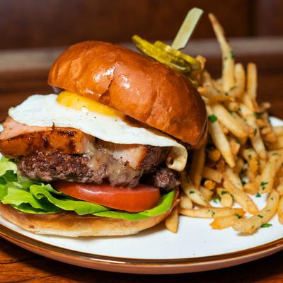 Cheeseburger, with sunny side up egg, pork belly, lettuce, tomato, and fries.