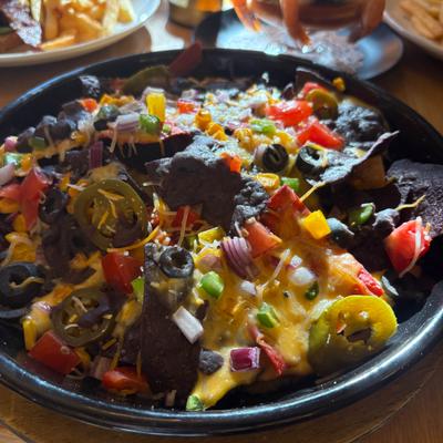 Nachos topped with melted cheese, jalapenos, olives, and peppers.