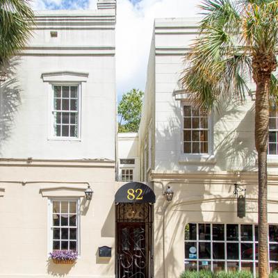 White building with a black awning labeled 82 and a palm tree in front
