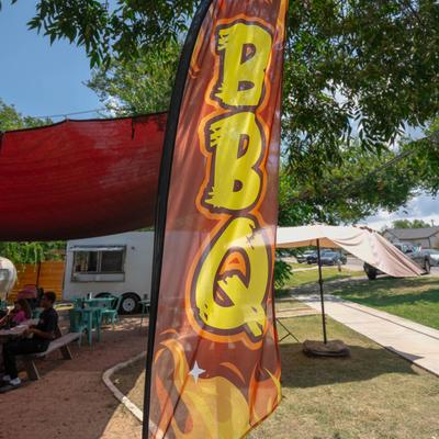 BBQ banner flag with bold yellow letters at outdoor seating area.