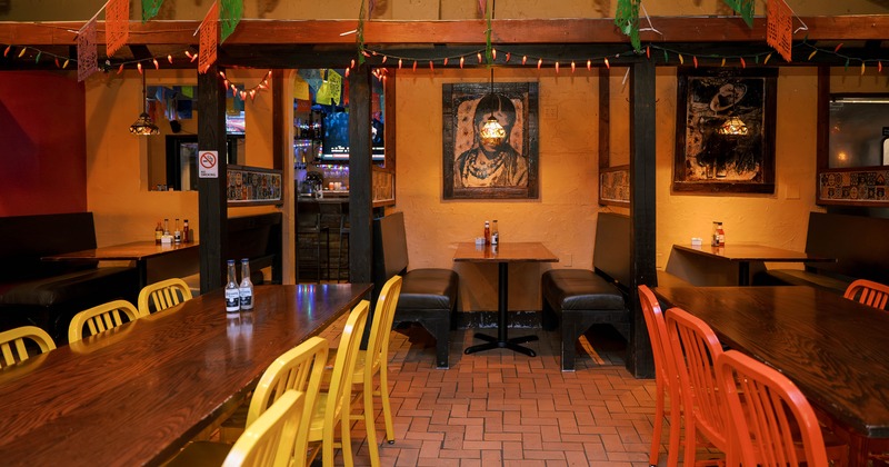 Mexican-style cozy interior dining area with wooden tables and chairs and booths along the wall