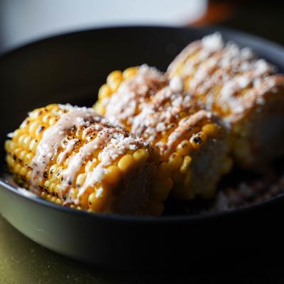 Mexican grilled corn on the cob topped with crema, cheese, and chili powder.