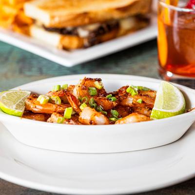 Glazed Shrimp topped with chopped green onions and lime wedges in a white bowl.