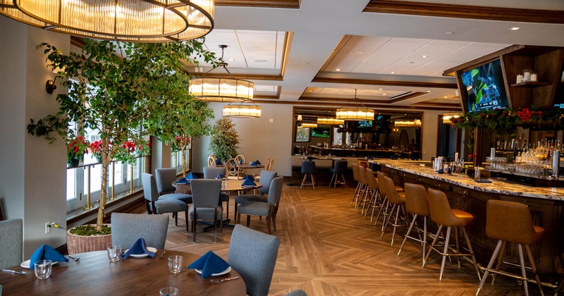 Interior dining area with wooden tables, gray chairs, and a marble bar