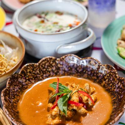 Thai spread featuring a rich curry, soup, sides, and a purple drink.