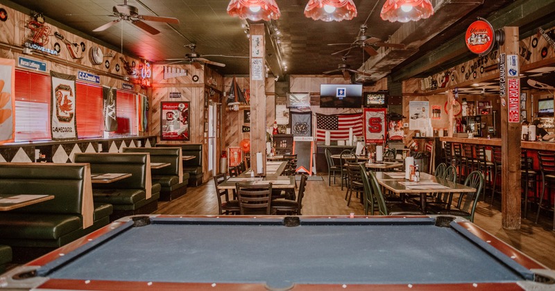 Pool table in the front of seating tables and booths