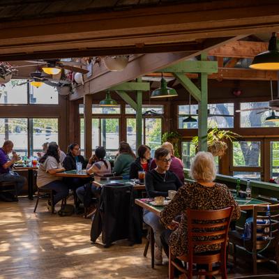 People chatting at sunlit restaurant tables.