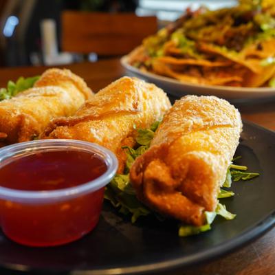 Crispy egg rolls served alongside red dipping sauce.