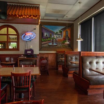 A casual restaurant interior with wooden booths, tables, and neon beer signs.