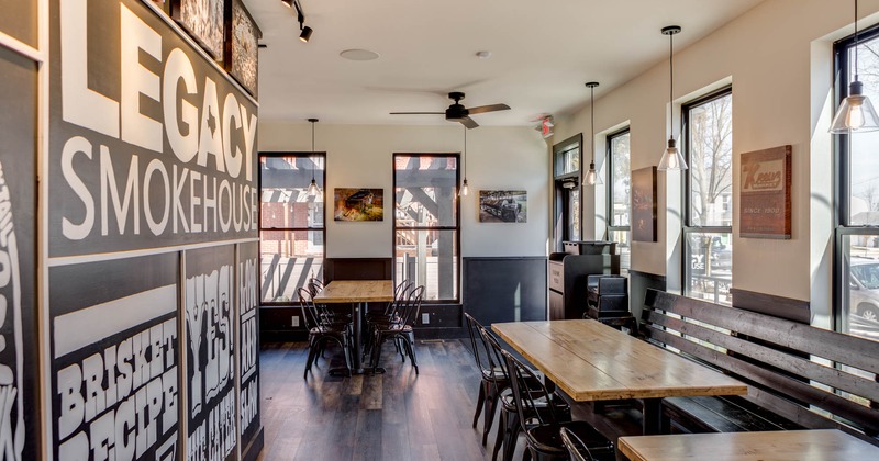 Interior, seating area, long bench with tables and chairs, restaurant logo print on the wall