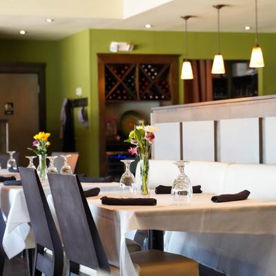 Dining area, white-clothed dining tables with dark chairs and floral arrangements.