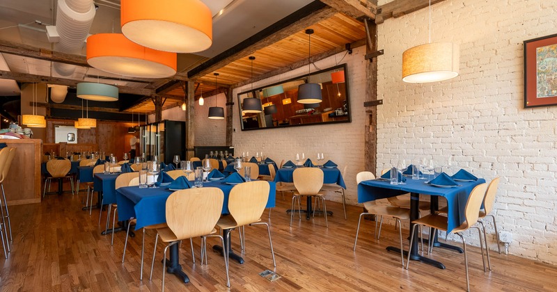 Interior with blue-covered tables, wooden chairs and white brick walls