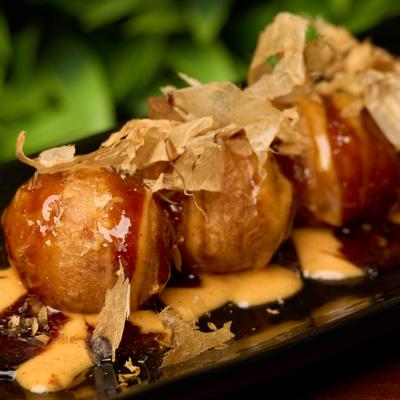 Takoyaki balls topped with bonito flakes and sauce drizzle.