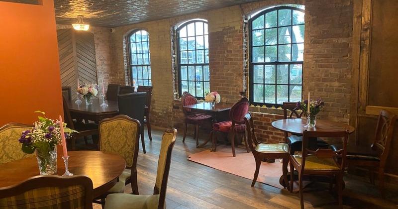A cozy interior - wooden floors, exposed brick walls, arched windows, vintage-style furniture
