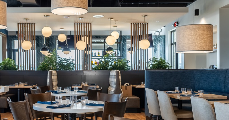 Modern dining room with booth seating, round tables, and pendant lights