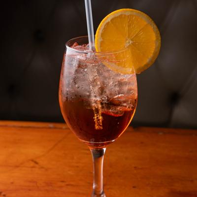 Aperol Spritz served in a wine glass with orange wheel garnish.