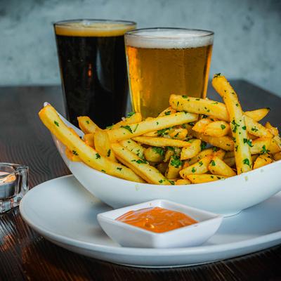 Garlic truffle fries served with sauce on the side and draft beers.