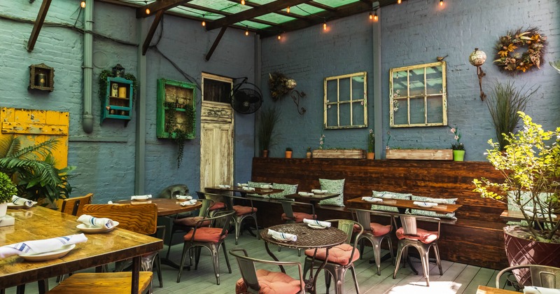 Dining area with wooden tables, metal chairs with cushions and vintage decor